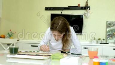 坐在桌旁，一个红发的<strong>小美女</strong>用颜料和画笔作画